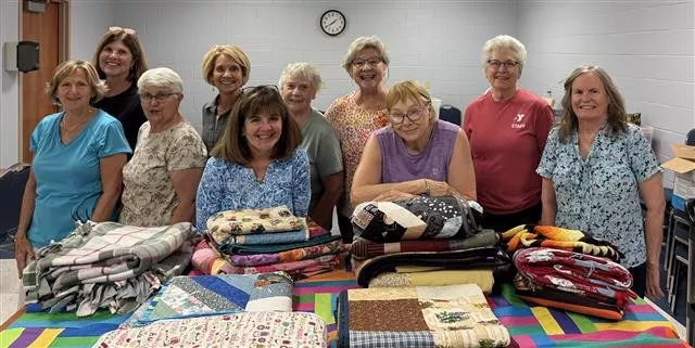 A group of women posing with their quilts