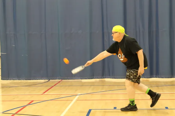 man in black shirt playing pickleball
