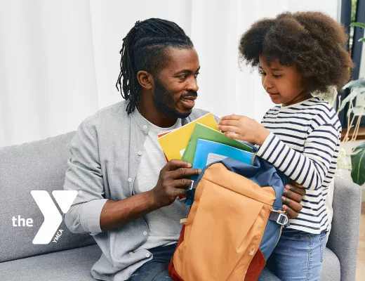 Father and daughter packing her backpack for school