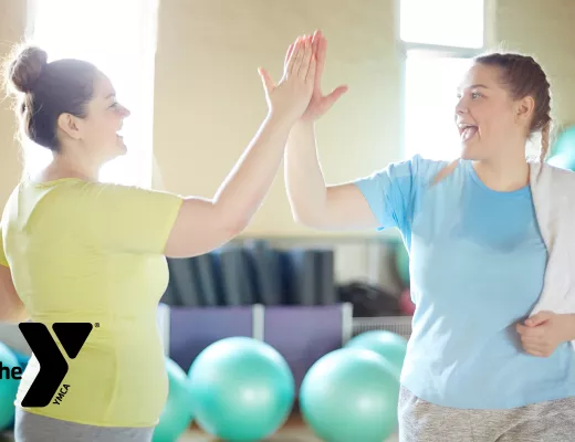 Two women high-fiving after a workout