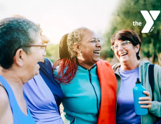 Four older adult women laughing while taking a walk outside