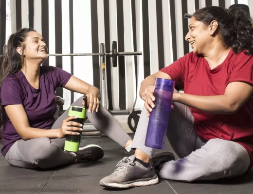 two women smiling holding water bottles