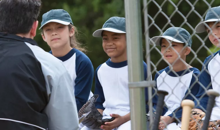 Baseball coach talking to young team