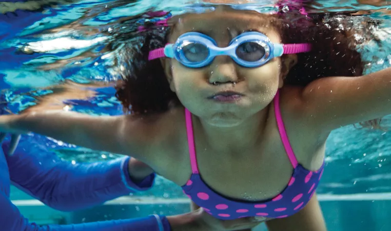 Young girl practicing swimming underwater