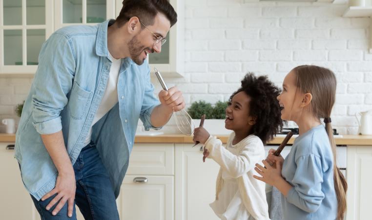 Dad and daughters dancing in a kitchen