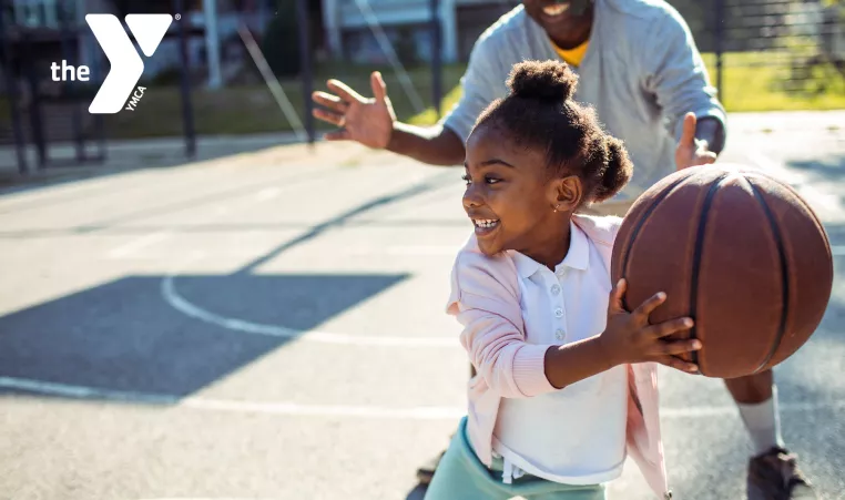 girl playing basketball with family