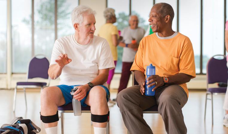 Two senior men chatting in a group fitness class