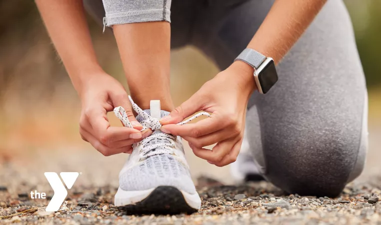 Woman kneeling outside to tie running shoe