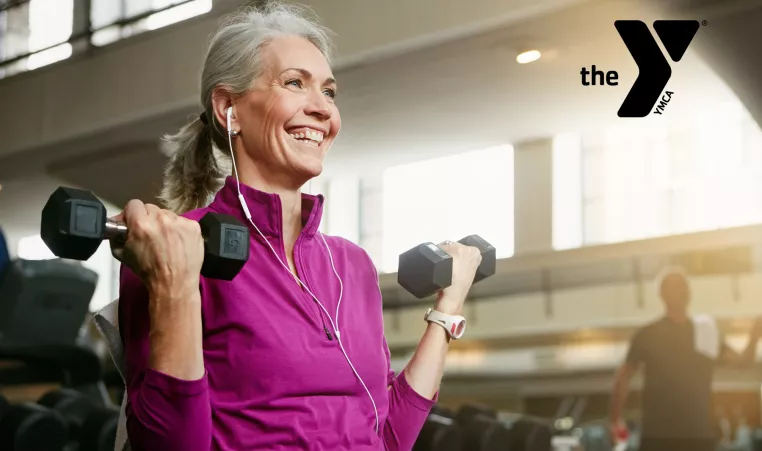 Older adult woman smiling while lifting weights