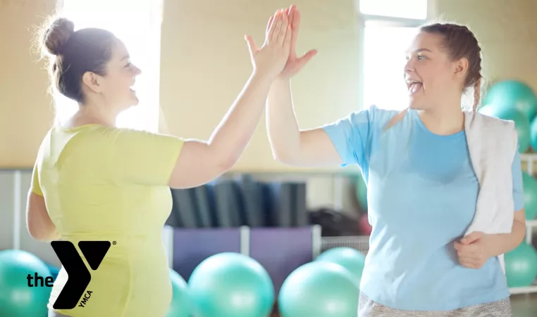 Two women high-fiving after a workout