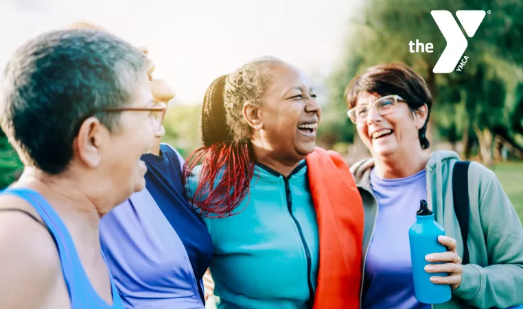 Four older adult women laughing while taking a walk outside