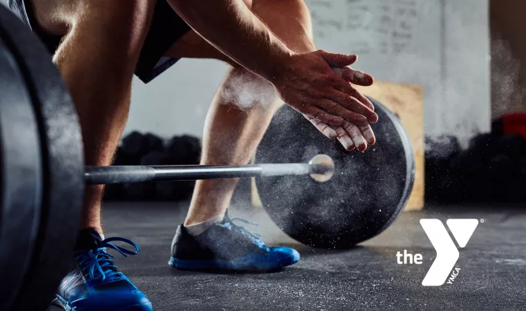 Closeup of a man's hands and lower body as he is about to deadlift.