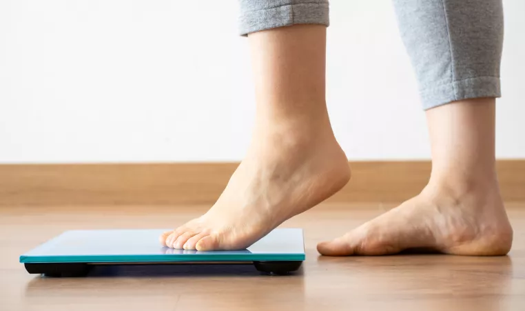 A woman's feet about to step on a scale