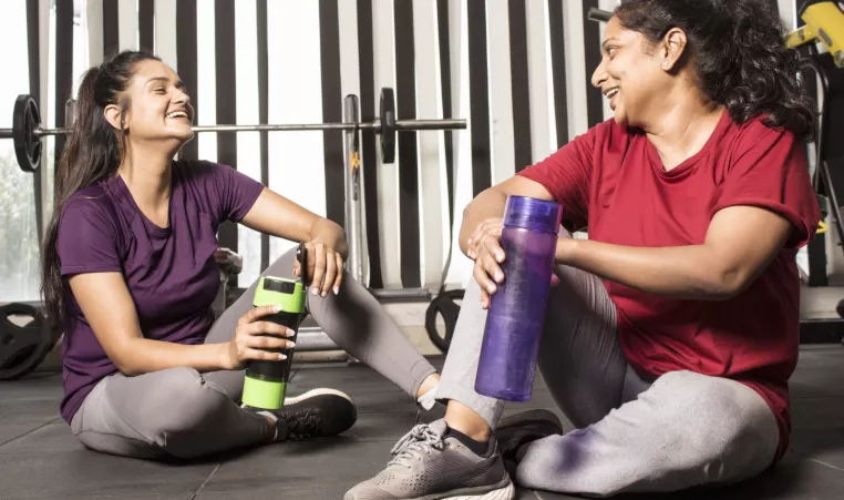two women smiling holding water bottles