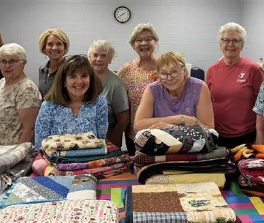 A group of women posing with their quilts