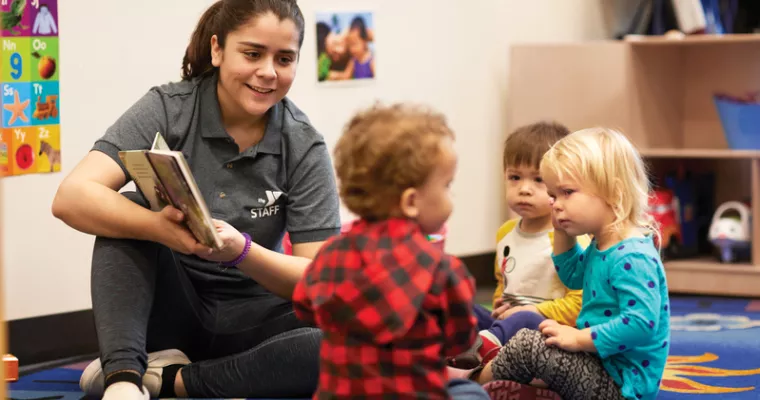 Childcare staff reading to toddlers
