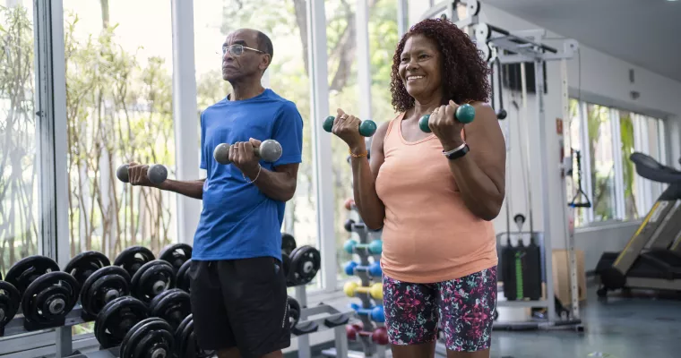 Black couple lifting weights in a gym