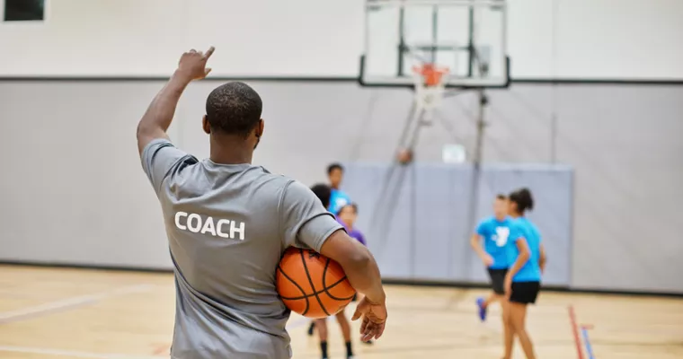 Basketball coach working with kids on a court.